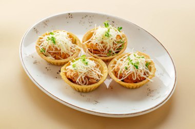 Kremalı tartlar, parmesan peyniri ve bir tabakta otlar.