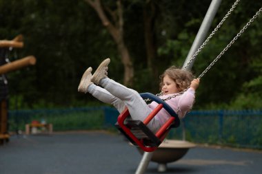 Çocuk parkında sallanan kızın yan görünüşü