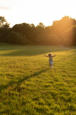 Çocuk parkta elleri havada yürüyor..