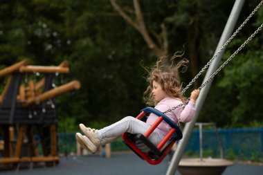 Çocuk parkında sallanan kızın yan görünüşü
