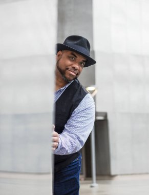 Dışarıda şapkalı bir zenci gülümsüyor.