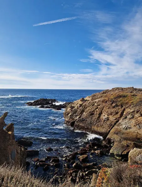 Açık mavi gökyüzünün altında kayalık uçurumlarla manzaralı bir sahil manzarası