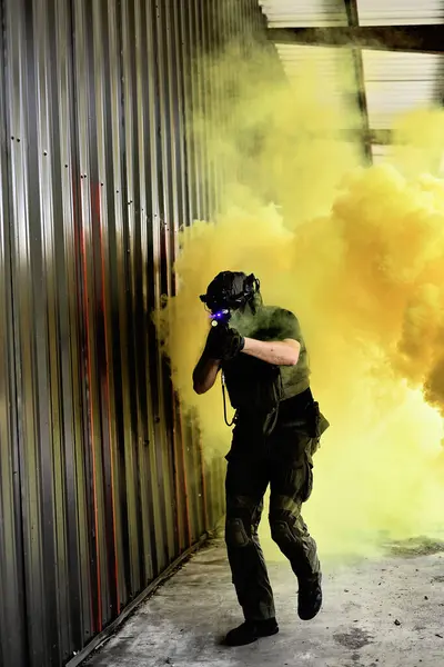 Dişli erkek hava yumuşağı oyuncu sarı dumanın içinde yürüyor