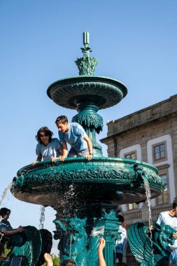 Yeni öğrenciler kutlama yapıyor ve yıldızlı su çeşmesine tırmanıyor.