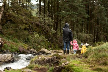 Çocukları olan baba dere kenarında orman yolunda duruyor..