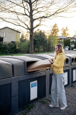 Kadınlar karton çöpleri geri dönüşüm kutularına koyar.