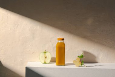 Bir şişe meyve suyu, dilimlenmiş yeşil elma ve zencefil kökü..