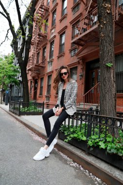 Ekose ceketli, New York sokaklarında neşeli bir genç kadın.