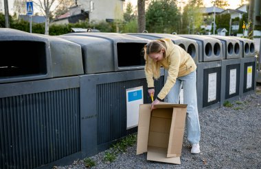 Kadınlar karton çöpleri geri dönüşüm kutularına koyar.