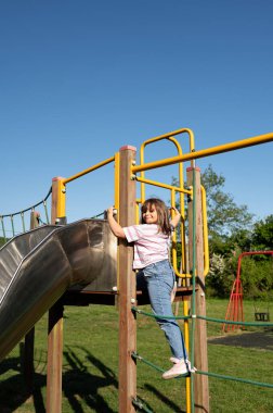 Gülümseyen çocuk kaymak için tırmanıyor. Dikey çubukta asılı.