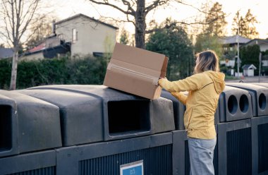 Kadınlar karton çöpleri geri dönüşüm kutularına koyar.
