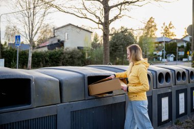 Kadınlar karton çöpleri geri dönüşüm kutularına koyar.