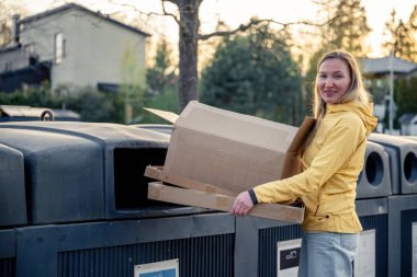 Kadınlar karton çöpleri geri dönüşüm kutularına koyar.