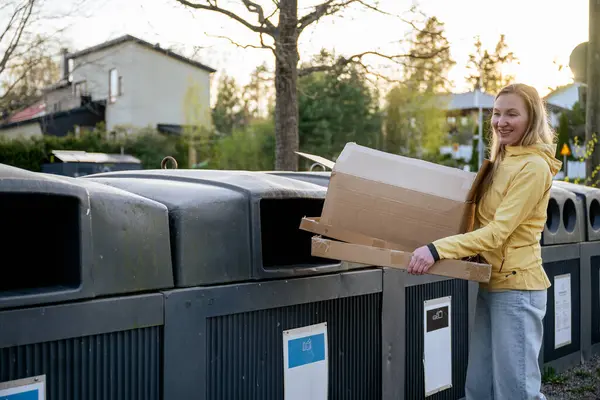 Kadınlar karton çöpleri geri dönüşüm kutularına koyar.