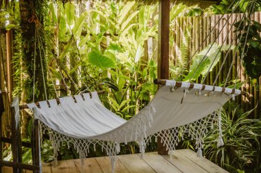 Yaz tatilinde yeşil bitkilerle dolu boş beyaz hamak.