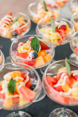 Yoğurt yağmuru ve nane şekerli meyve salatası fincanları.