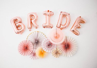 Duvarında pastel kağıt yelpaze olan altın renkli balonlar.