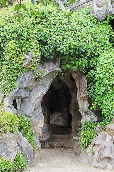 Yeşil sarmaşıkla kaplı taş mağara.