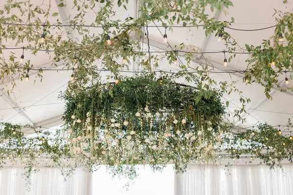 Çiçek yeşili avize, beyaz çadırda asılı ışıklar.