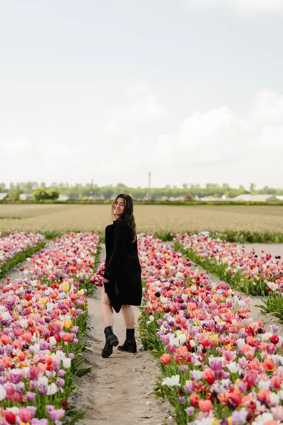 Çiçek açan lale tarlasında Yürüyen Kadın Arkasına Bakıyor