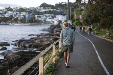 Erkeksi sahil gezintisinde yürüyen adam manzaranın tadını çıkarıyor.