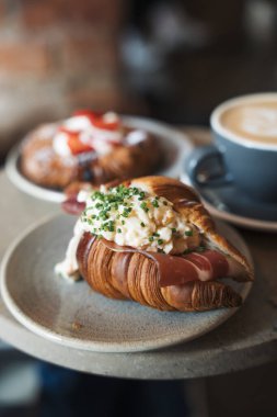 Yumurta ve jambon taze pişmiş kruvasan bir kafede masanın üstünde.