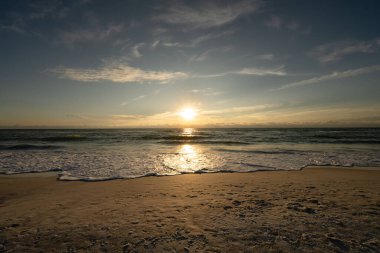 Muhteşem bir tropik gün batımının altında kumdaki ayak izleri.