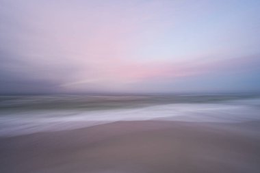 Florida sahilinin üzerinde durgun pembe, mor ve mavi pastel güneş doğuyor.