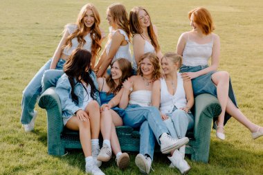 Dışarıda kanepede gülümseyen ve rahatlatan sekiz kız öğrenci yurdu.