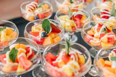 Yoğurt yağmuru ve nane şekerli meyve salatası fincanları.