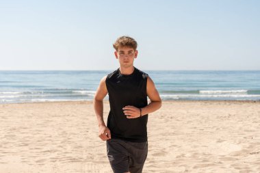 Başlık: Aktif Genç Adam Güneşte Sahilde Koşuyor