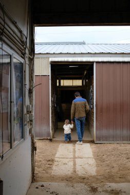 Milenyum Baba ve Küçük Kız El ele tutuşup At Ahırında Yürüyorlar