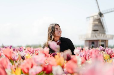 Geleneksel Hollanda Değirmeni ve Lalelerin Önünde Gülümseyen Kadın