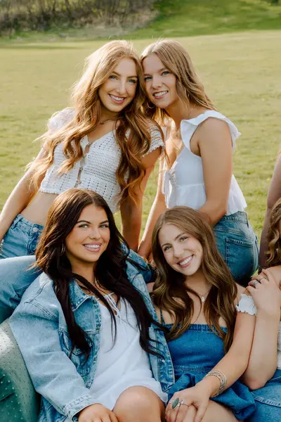 Üniversiteden dört oda arkadaşı kampüs bahçesinde birlikte gülümsüyor.