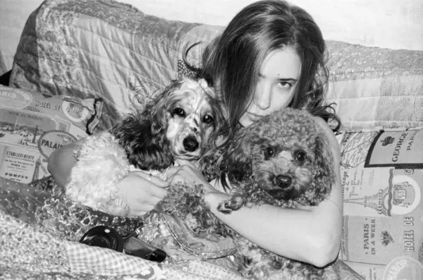 Düşünceli bir kadın, köpeklerini rahat, modern bir koltukta kucaklıyor.