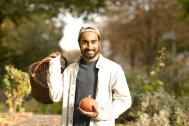 Bahçede sepet toplayan genç adam.