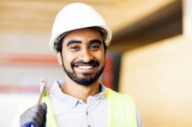 Ahşap bir binada beyaz kasklı ve güvenlik yelekli bir işçi.