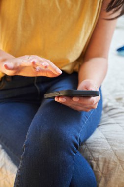 Kadın cep telefonundan bir şey dinlemek üzere.