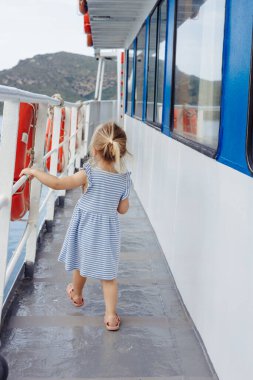 Genç bir kız feribot güvertesinde yürüyor, gezinin tadını çıkarıyor.