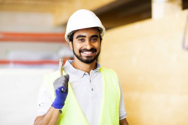 Ahşap bir binada beyaz kasklı ve güvenlik yelekli bir işçi.