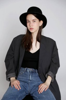 Şapkalı ve kot pantolonlu genç bir kadın model. Stüdyoda portre