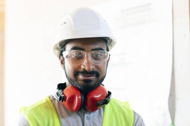 Portre, ahşap bir binada miğferli işçi.