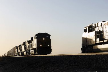 İki siluetli tren son gün batımında buluşuyor.