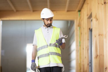 Ahşap bir binada beyaz kasklı ve güvenlik yelekli bir işçi.
