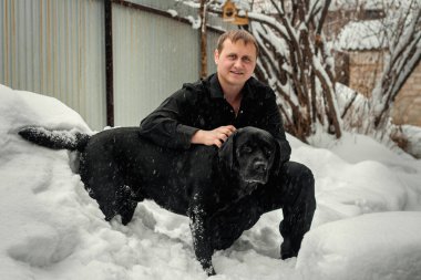Bir adam ve siyah bir Labrador Taze karda oynuyorlar