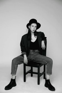 Şapkalı ve kot pantolonlu genç bir kadın model. Stüdyoda portre