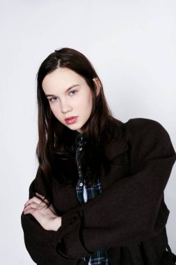 Stüdyoda palto giyen genç bir kadın.