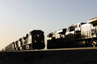 İki siluetli tren son gün batımında buluşuyor.