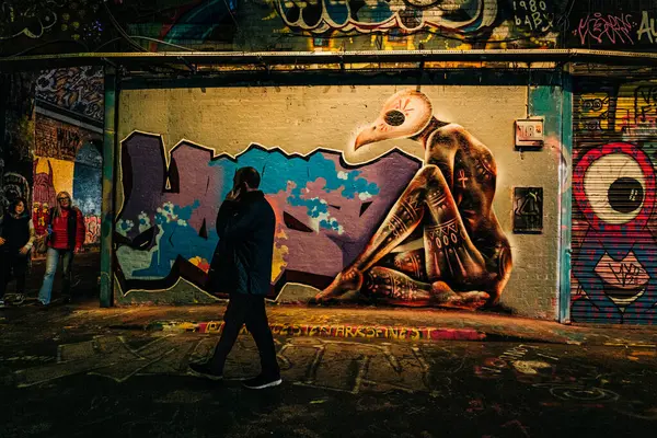 Adam şehir tünelinde büyük bir grafiti duvarının yanından geçiyor.