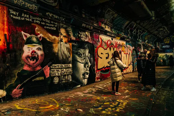 İnsanlar tünel galerisinde grafiti sanatını gözlemleyip fotoğraflarını çekiyorlar.